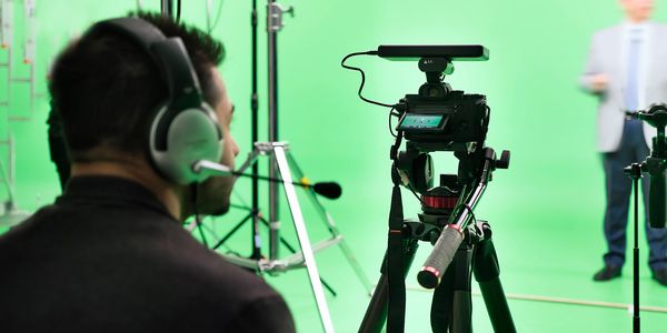 Person operating a camera in a green screen studio.