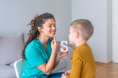 Speech therapist with child using letter S for speech therapy.