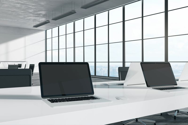 Empty laptop in bright coworking office with city view and sunlight. Mock up, 3D Rendering