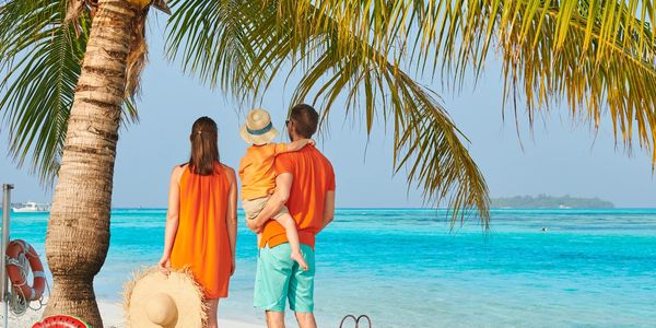 Family enjoying a tropical beach vacation under palm trees.