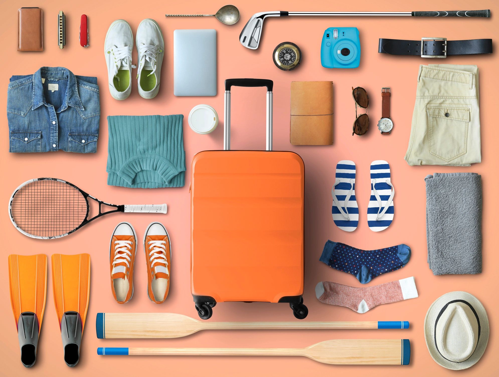 Flat lay of travel and sports gear with suitcase.