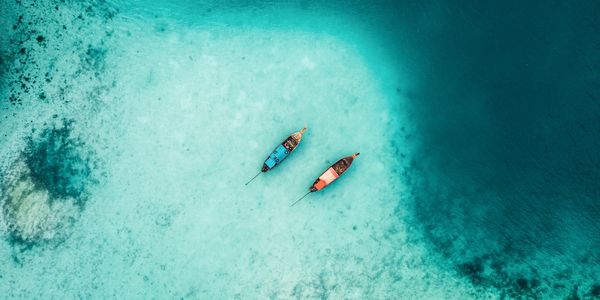 Two boats floating on clear turquoise water, seen from above.