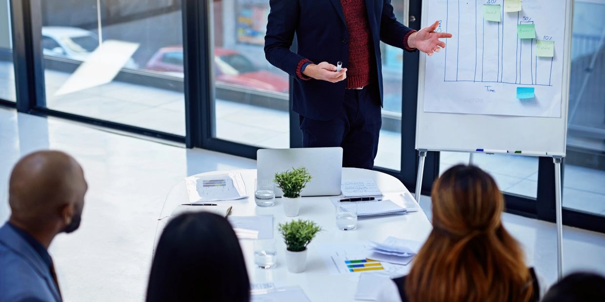 Businessman presenting data to colleagues in a modern office meeting.