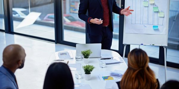 Man presenting business data to colleagues in a modern office meeting.