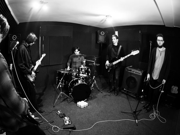 A black-and-white photo of a band rehearsing in a soundproofed room.