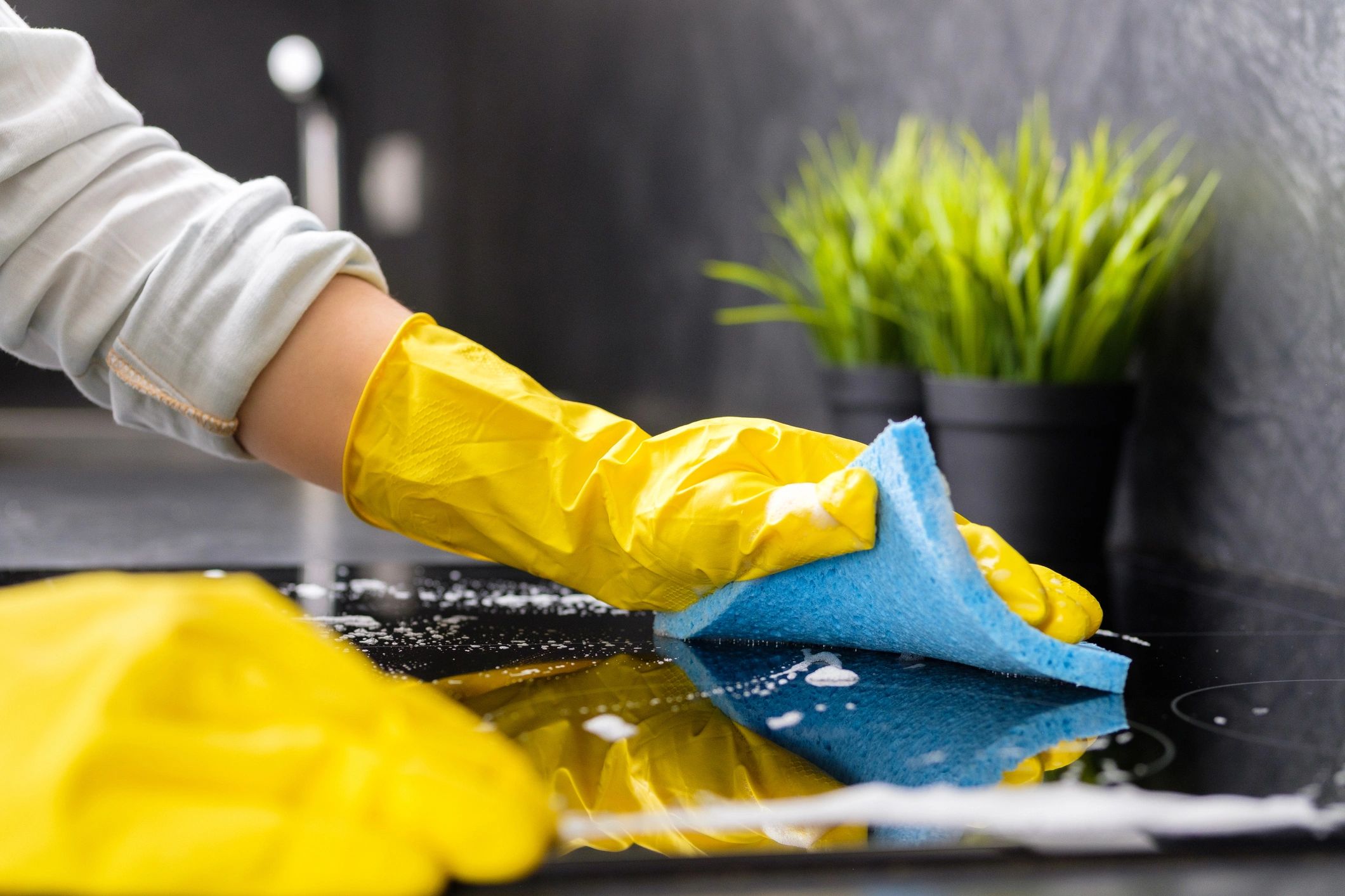 Person cleaning a black surface wearing yellow gloves.