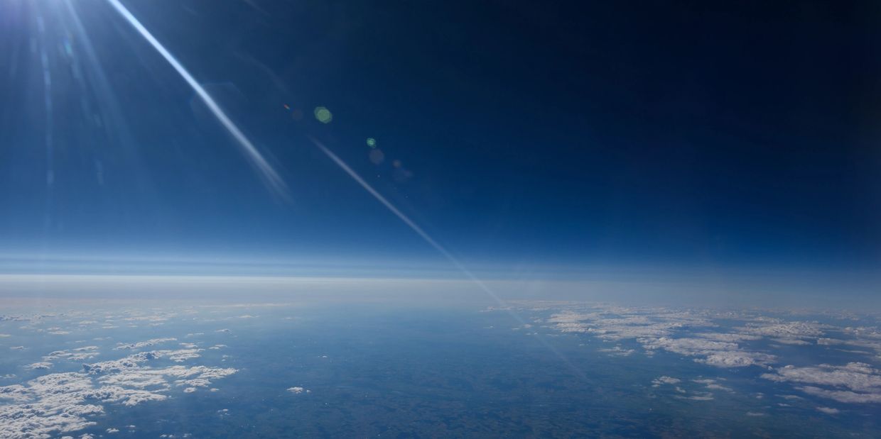View of Earth's horizon and atmosphere from high altitude with sun flare.