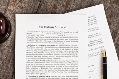 Non-disclosure agreement document with pen and judge's gavel on wooden table.