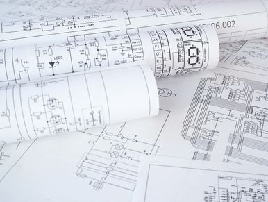 Rolled and spread out electrical circuit diagrams on a table.