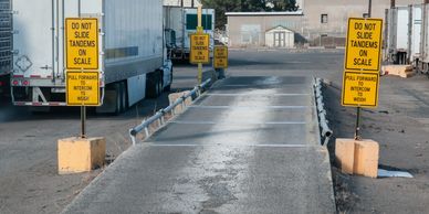 Truck weighing scale area with caution signs preventing tandem sliding.