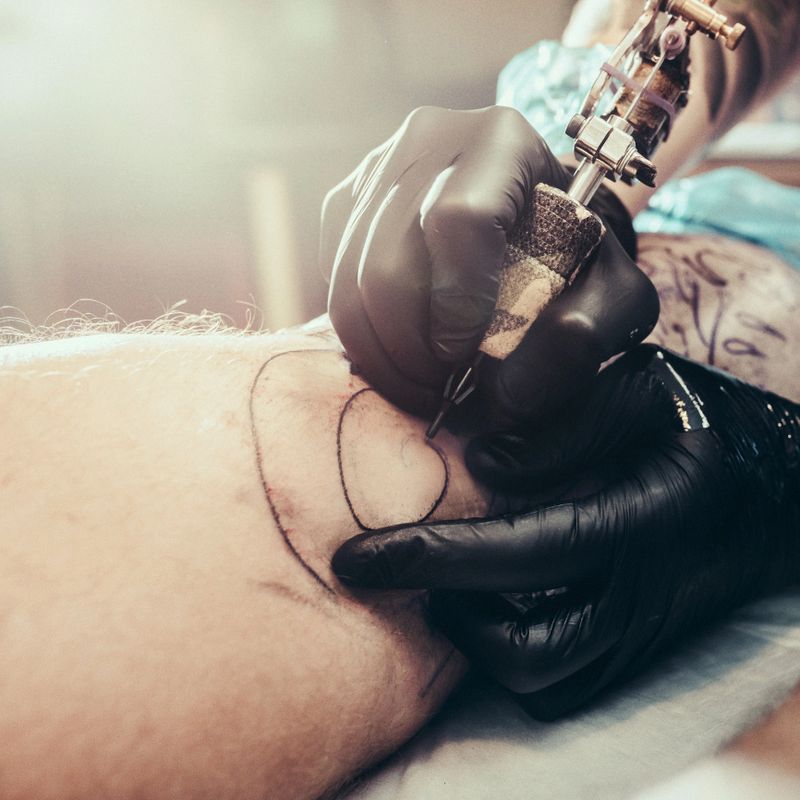 Tattoo master making tattoo on leg