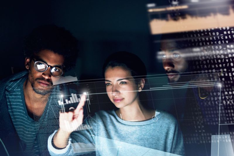 Shot of a group of programmers working on a computer code at night