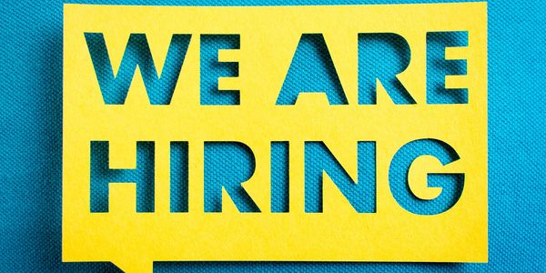 Yellow cutout text saying 'WE ARE HIRING' on blue fabric.