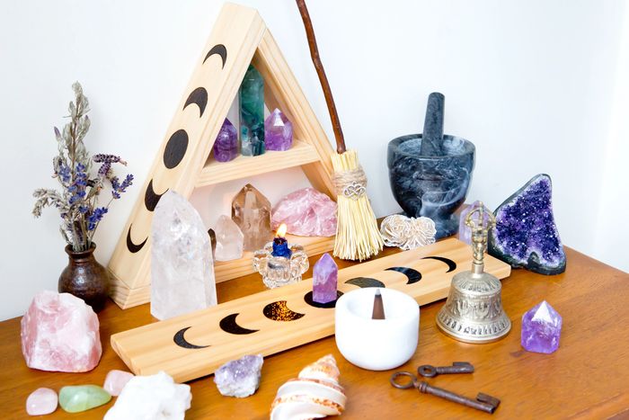 A wooden altar with crystals, a broom, incense, and spiritual symbols.