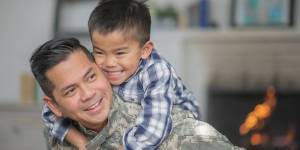 Asian Service member (male) carrying his son on his back. 