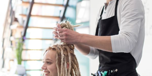Hairdresser styling dreadlocks in salon.