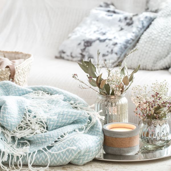 Cozy image with sofa, pillows, blanket, candle and floral arrangement