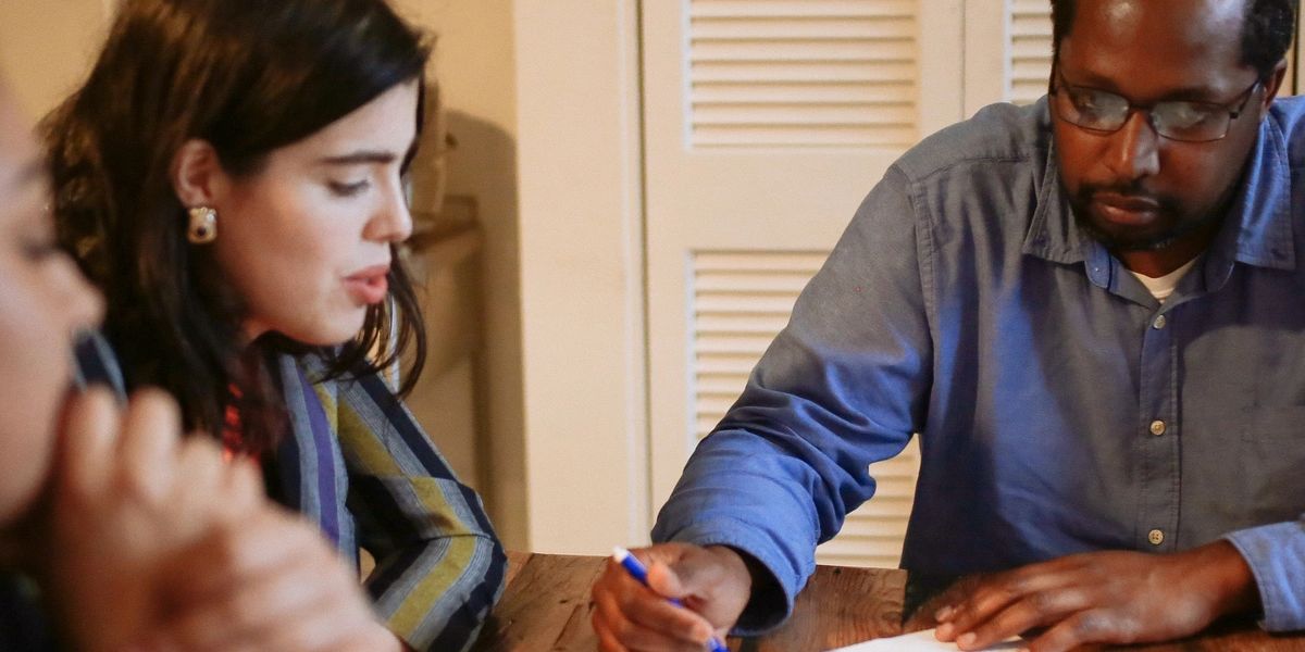 Homeowner writing a hardship letter at a desk with mortgage documents