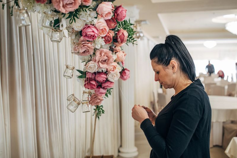 Classy wedding setting with flower decor, woman working on wedding decor.