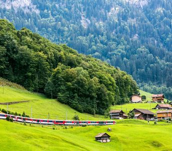 The red Bernina Express train travels through scenic snowy mountains.