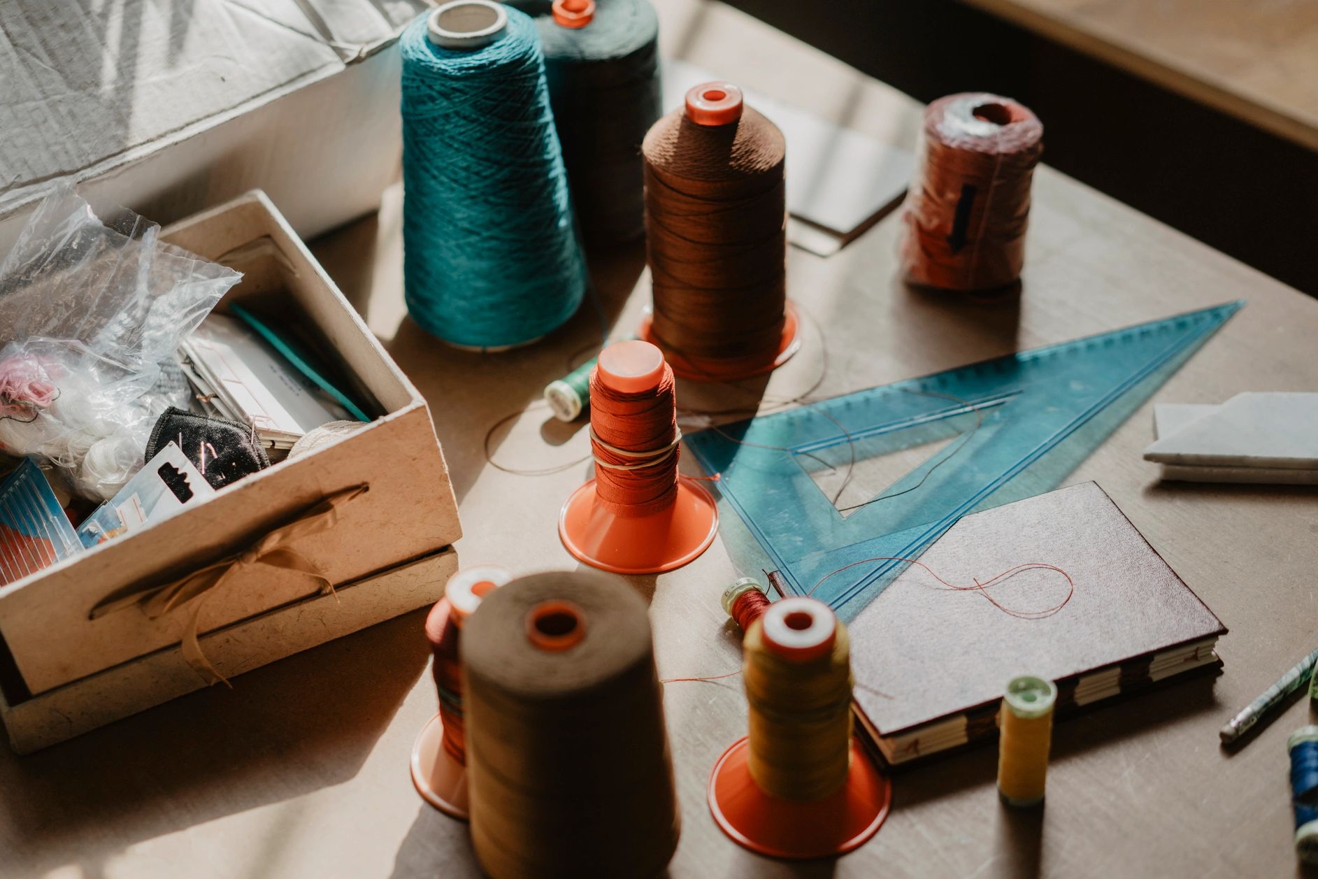 Spools of thread and sewing tools on a worktable with natural light.