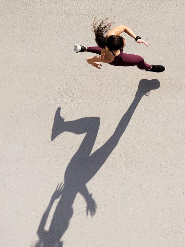 Mujer ejercitándose enérgicamente con sombra elongada.