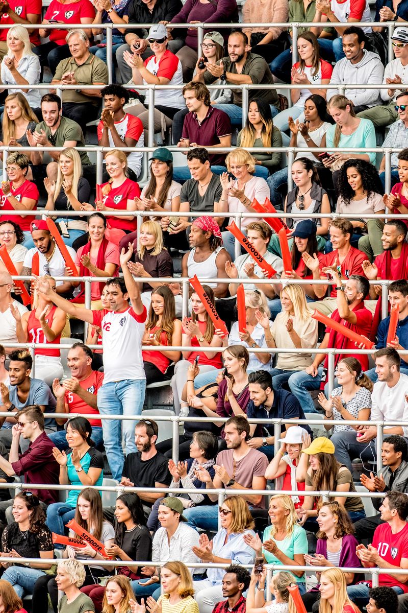 Vertical photo of a stadium crowd in red jerseys cheering for their team.