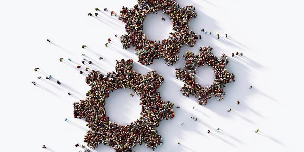A large group of people forming three interconnected gears on a white surface.