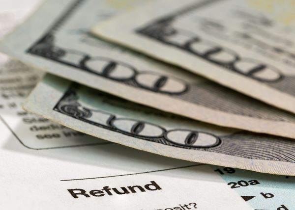 Tax refund form with hundred-dollar bills on top.
