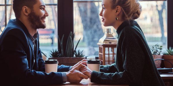 Couple holding hands and smiling at cafe.