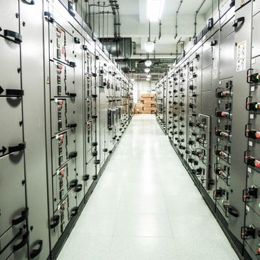 A corridor flanked by electrical control panels in an industrial setting.