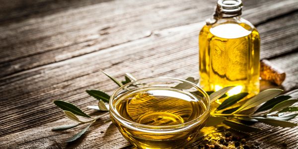 A bowl and bottle of olive oil with olive branches.