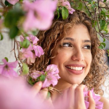Smiling woman surrounded by pink flowers.