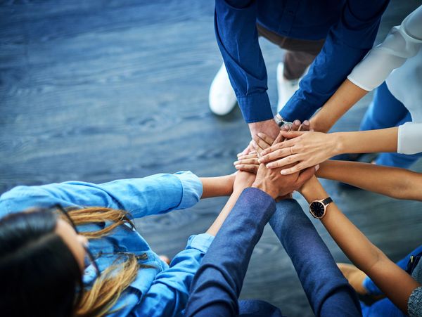 Group of diverse people stacking hands in teamwork gesture.