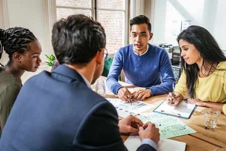 Diverse team collaborating over business charts and notes in a bright office.
