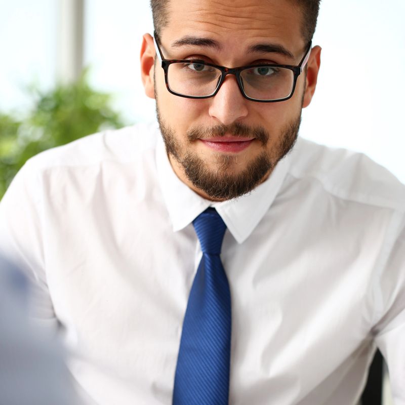 Handsome smiling bearded clerk man at office workplace with silver pen in arms do paperwork portrait. Staff dress code worker job offer client visit study profession boss market idea coach training