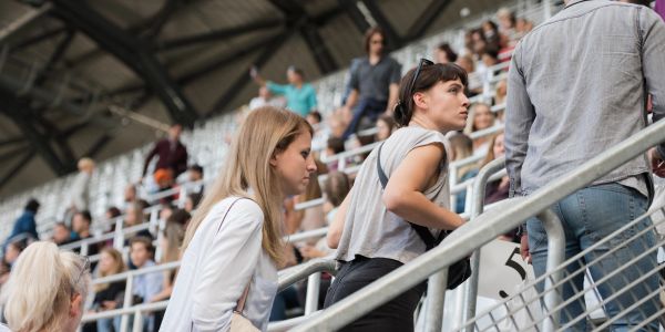 People standing in stadium seating area looking focused.