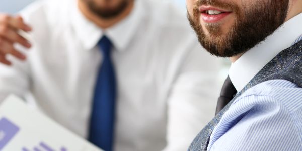 Two businessmen discussing documents with smiles in a professional setting.