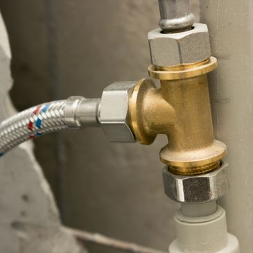 Close-up of a brass plumbing valve connected to pipes.
