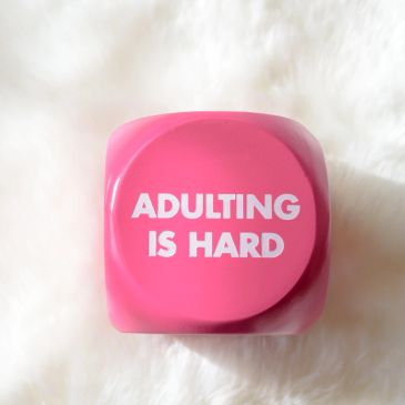 Pink stress ball with 'ADULTING IS HARD' text.