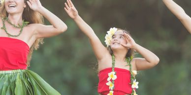 Girl dancing in a Hawaiian outfit with flower accessories.