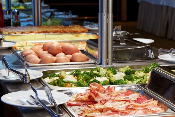 Hot buffet with chafing dishes of roast potatoes, sliced meats and vegetables at a Toronto event