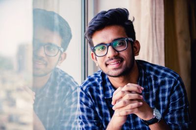 Young man in glasses smiling by a window.