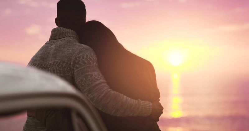 Rearview shot of an affectionate young couple watching the sunset at the beach
