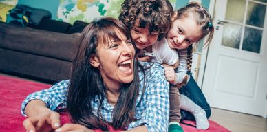 Mother joyfully playing with two children indoors.