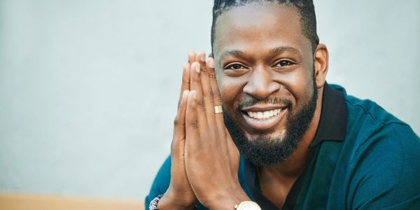 Smiling man with hands together in a friendly gesture.