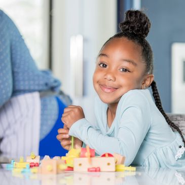 Smiling young girl playing with a wooden toy at home.
