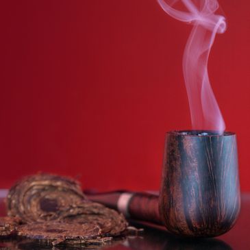 A smoking wooden pipe with tobacco against a red background.