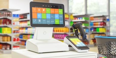 Modern POS system with touchscreen and barcode scanner in a colorful grocery store.
