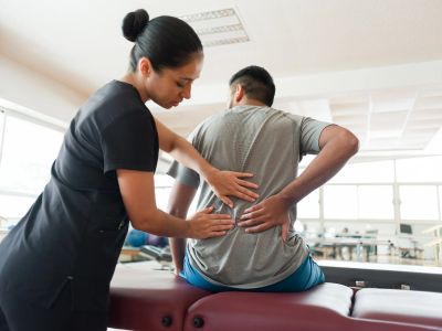 Therapist examining a man with back pain.